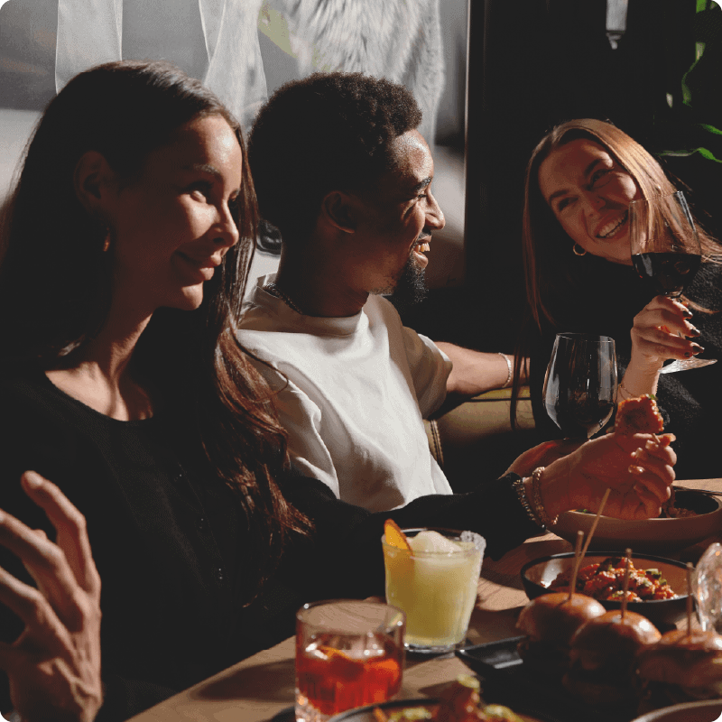 Group of people smiling while drinking wine and sharing appetizers