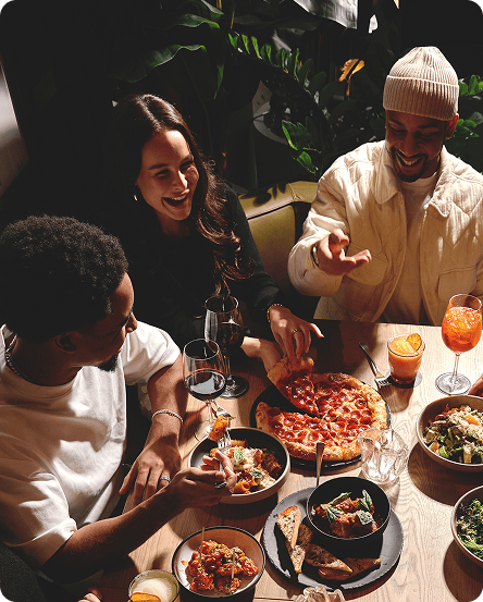 Group of people eating around a table full of shareable plates and cocktails at King Taps